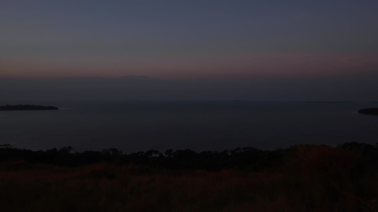 Time lapse of sunset over Lake Victoria. View of archipelago (Ssese Islands) from hill in Kalangala, Uganda. Gusts of wind on water, islands and horizon showing