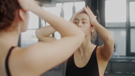 woman checking her hair in the gym