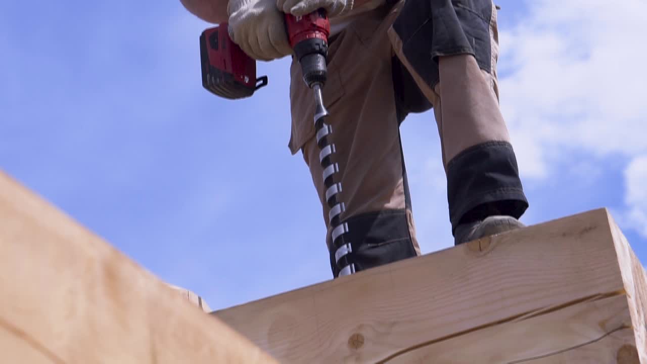 Construction Worker Drilling Wooden Beams