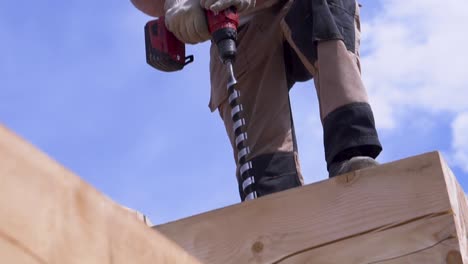 trabajador de la construcción perforando vigas de madera