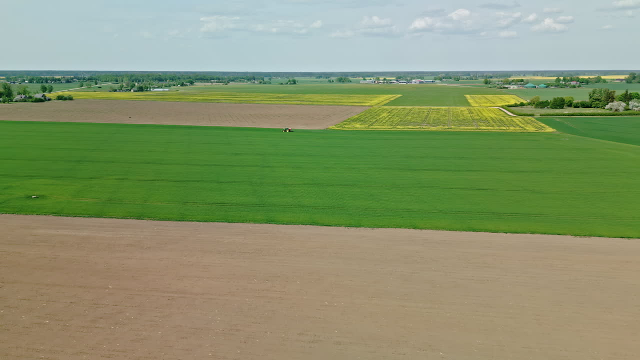 трактор на сельскохозяйственном поле в ровной сельской местности - воздушный толчок вперед