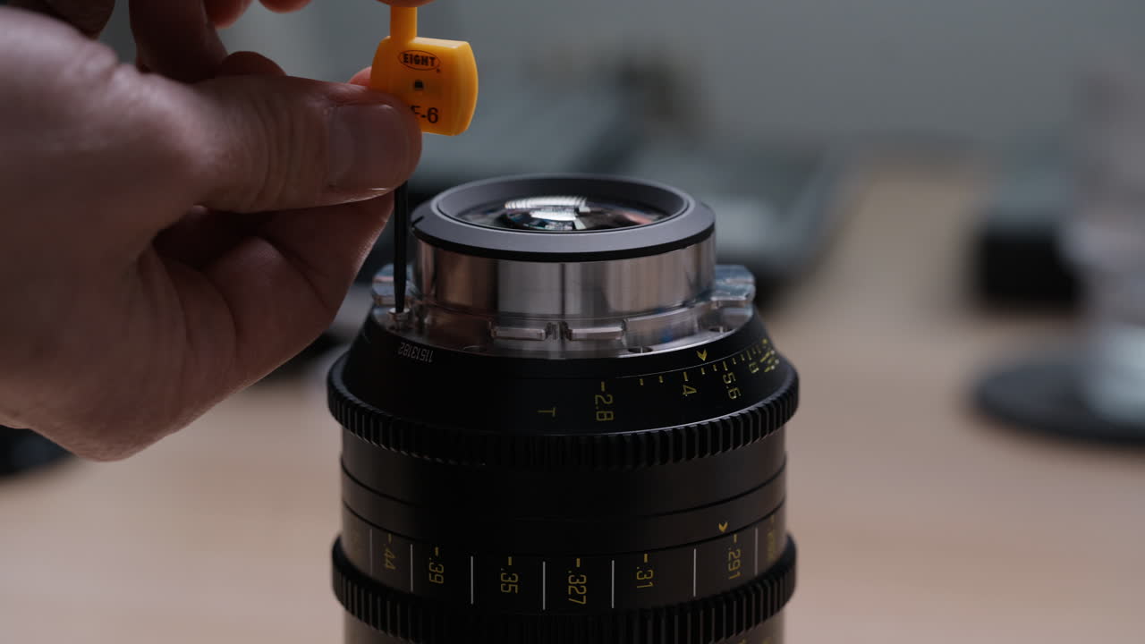 Vue latérale de mains plaçant et ajustant soigneusement une monture à baïonnette PL sur un objectif cinéma. Assemblage fluide et précis clairement visible. Dernière étape d'une conversion EF vers PL.