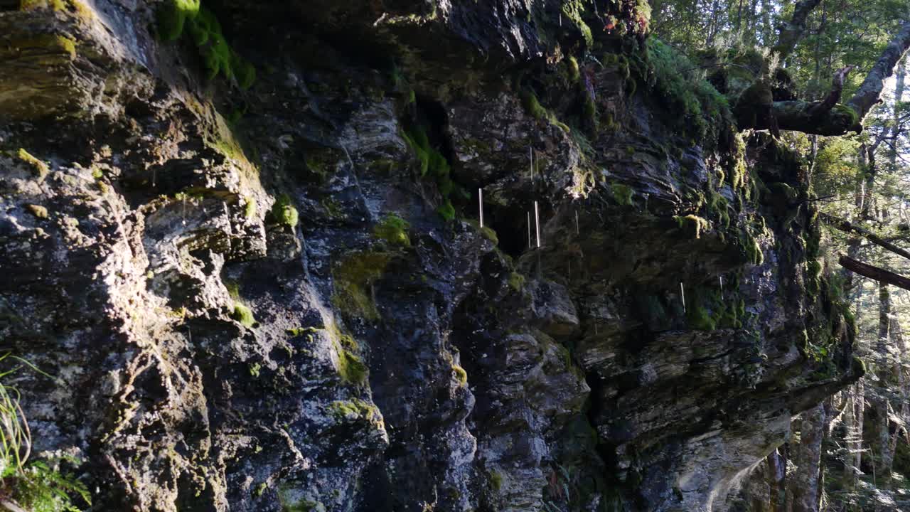 cerca de gotas de agua cayendo por un acantilado de montaña rocosa en el parque nacional de nueva zelanda durante el verano