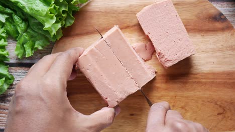 cortar un bloque de carne procesada en una tabla de madera