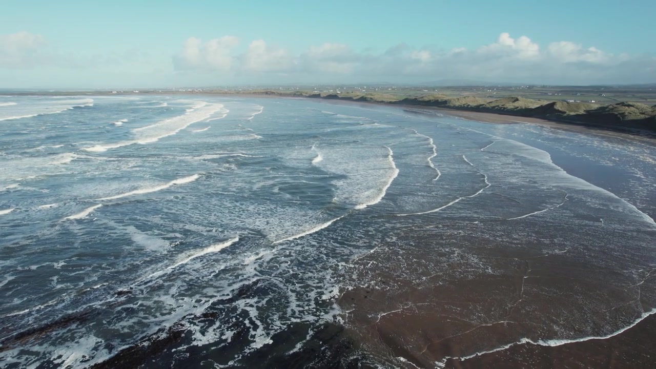 Ripresa con drone della spiaggia di Doughmore con la bassa marea, onde marine sulla riva sabbiosa nella Contea di Clare, Irlanda
