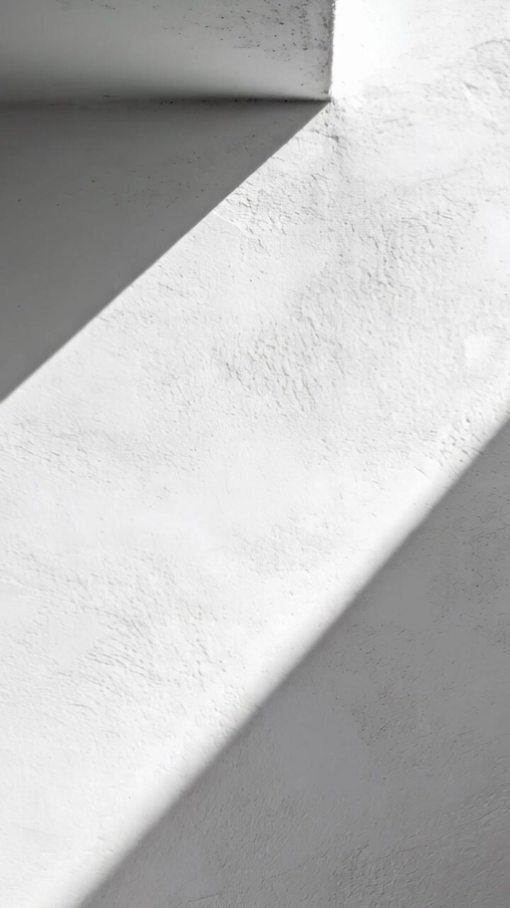 Vertical video: Sunlight through window casting diagonal strip on plaster corner, shifting shadows