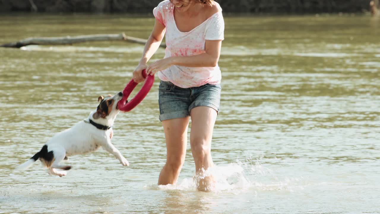 Donna che gioca con il cane vicino al fiume