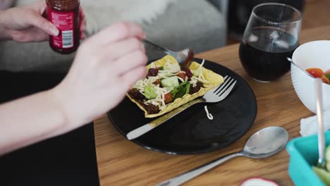 Putting-some-chipottle-paste-on-vegan-minced-soy-meat-laying-on-a-hard-shell-tortilla