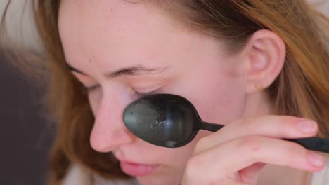 young woman applying face mask with spoon