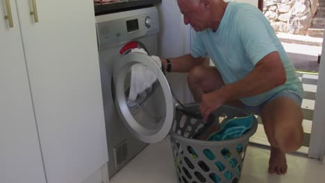 Caucasian-senior-man-removing-clothes-from-washing-machine-at-home