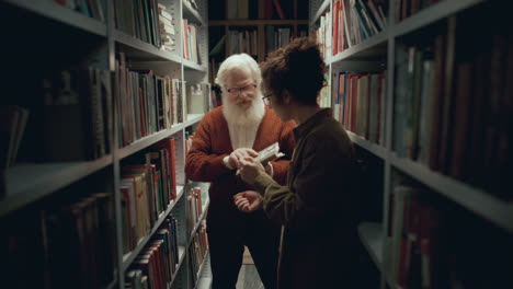 elderly professor and young student discussing book in college library