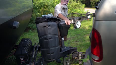 elderly man adjusts rv hookup while talking to someone and motioning how far away it was