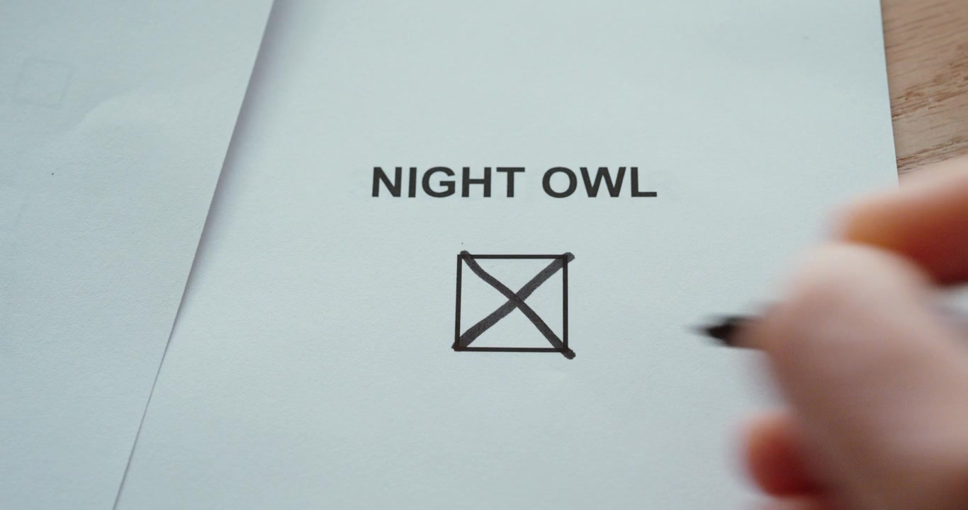 Close-up of a hand marking the night owl checkbox on a paper form, representing late-night habits and nighttime lifestyle.