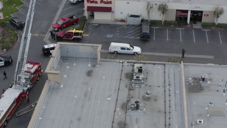 a funeral procession, lead by a white hearse approaches a building