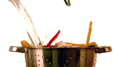 rebanadas de pimienta y agua que caen en el colador