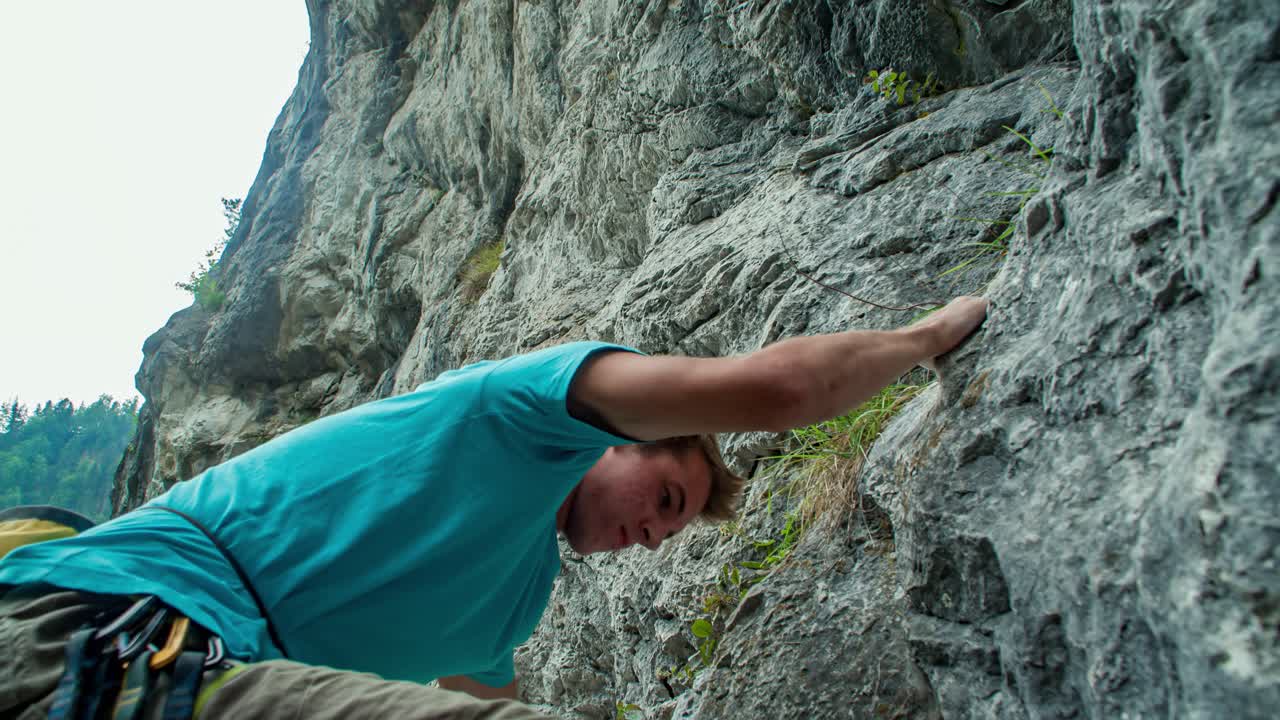 Young man climbs a rocky wall with bare hands in Burjakove peci, Slovenia