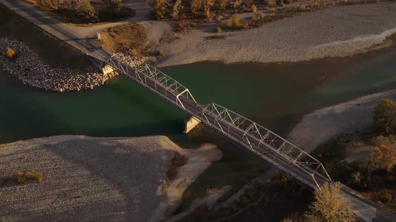 4k aerial footage of an old steel truss bridge in southern Alberta, Canada at sunrise. Cinematic camera movement with gimbal 45 degrees downward filming the structure from high above