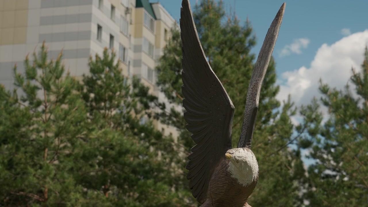 Majestetisk ørneskulptur i tre med utspredte vinger i en park