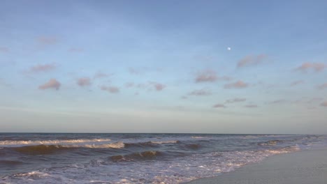 sky and moon with waves on a sandy caribbean sea beach during sunset