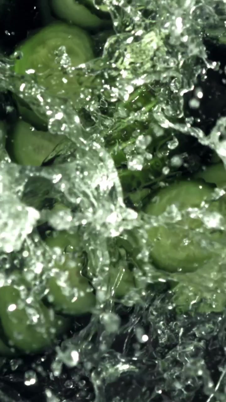 Fette di cetriolo fresco che schizzano nell'acqua al rallentatore
