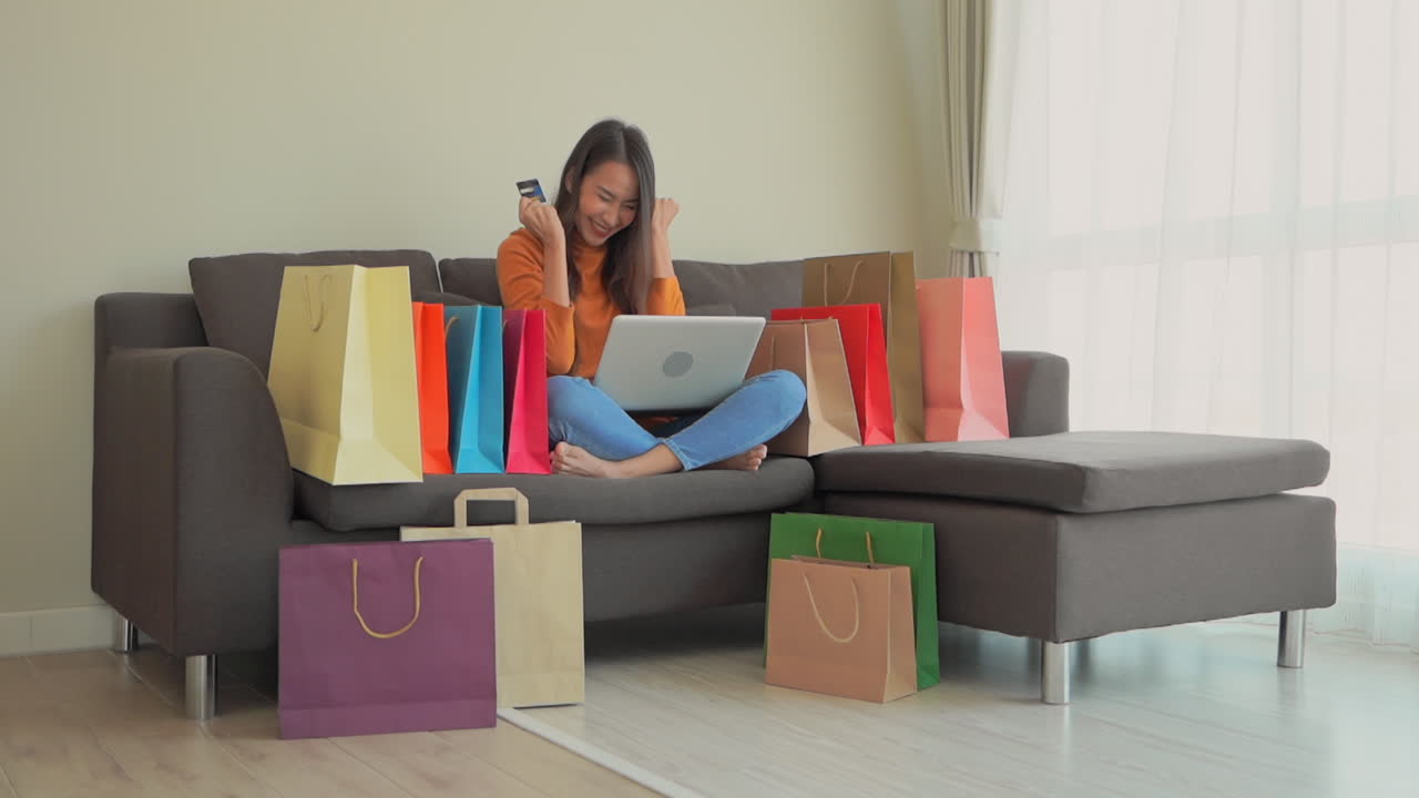 Excited young Asian girl uses her laptop and credit card to buy online