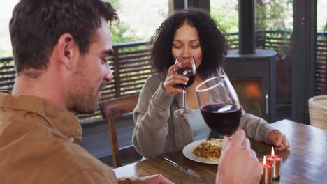 smiling mixed race couple drinking wine and having lunch at a restaurant