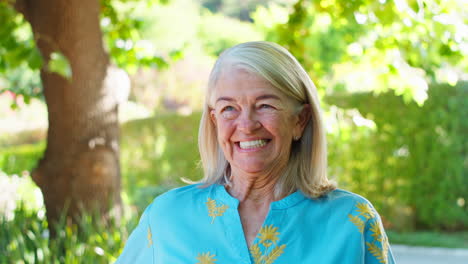 portrait of smiling senior woman standing outdoors in garden park or countryside