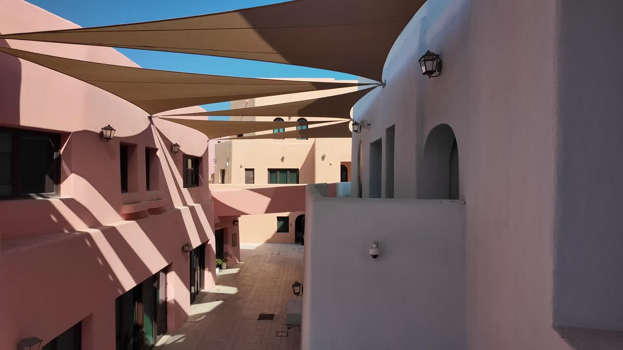 Sunny Courtyard with Pink and White Buildings and Shade Sails