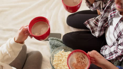 women friends enjoying hot chocolate and popcorn, celebrating christmas together at home