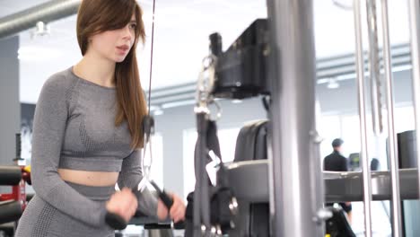 young caucasian fit woman doing cable cross over chest exercise at the gym