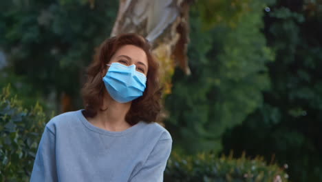 [camera used: canon c300] caucasian woman wearing a surgical face mask and smiling while outside