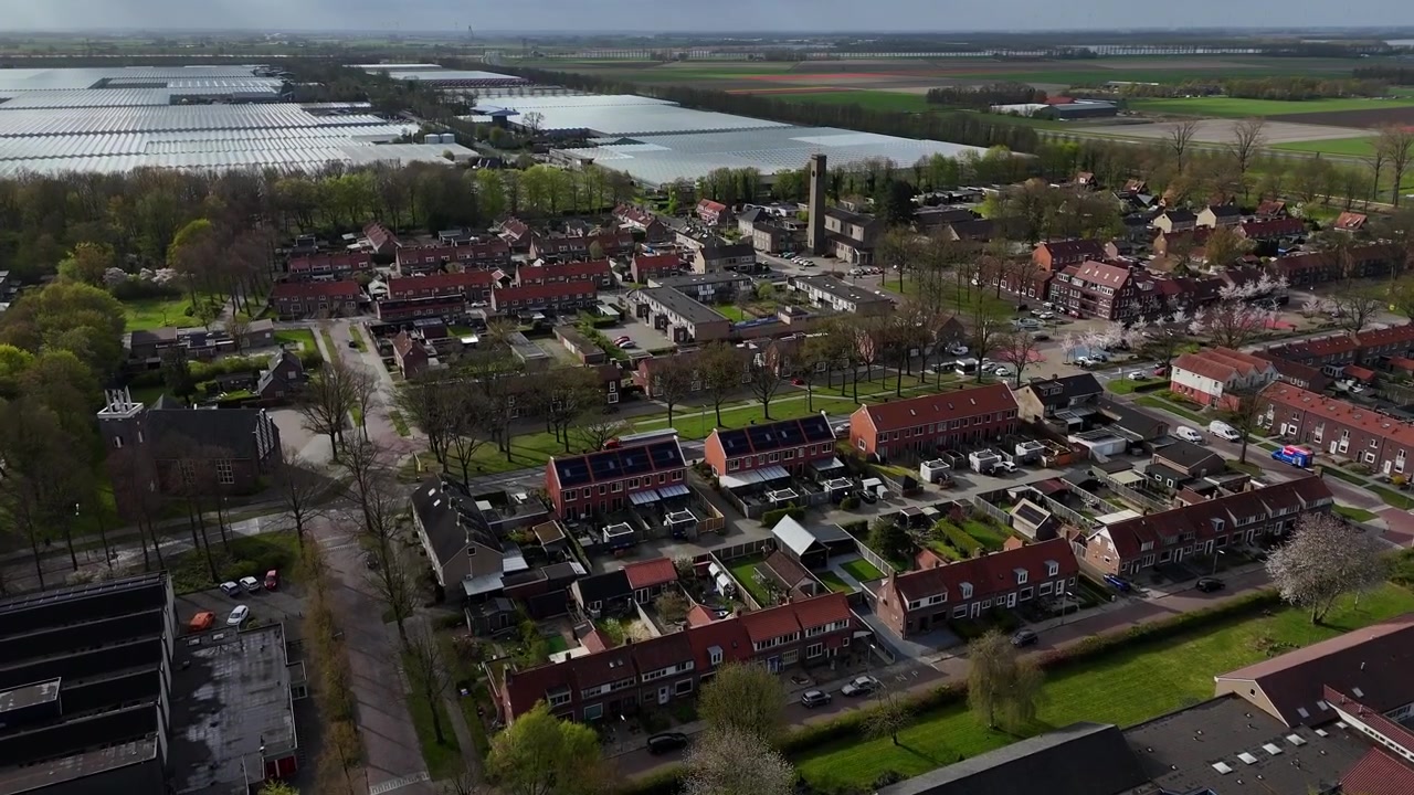 Dronebeelden van het Nederlandse dorp Ens, Noordoostpolder, Flevoland, Nederland. Lange clip van het dorpscentrum met kassen.