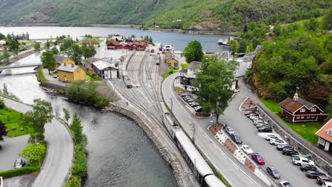 aerial: train by a river entering flåm station