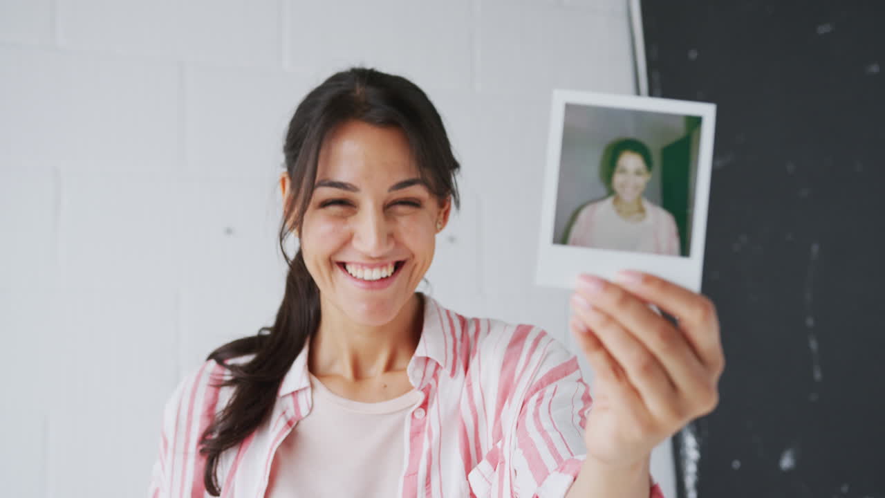 ritratto di una fotografa in una ripresa fotografica che tiene in mano una stampa polaroid istantanea in studio
