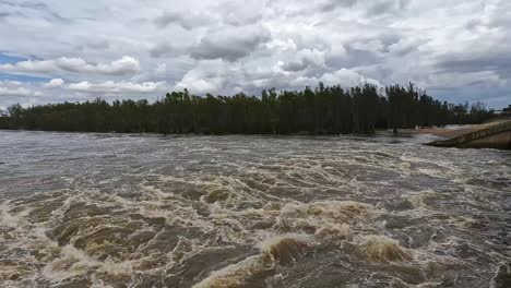 gente caminando sobre el puente del vertedero de yarrawonga y panoramizando hacia el río murray hinchado y que fluye rápidamente