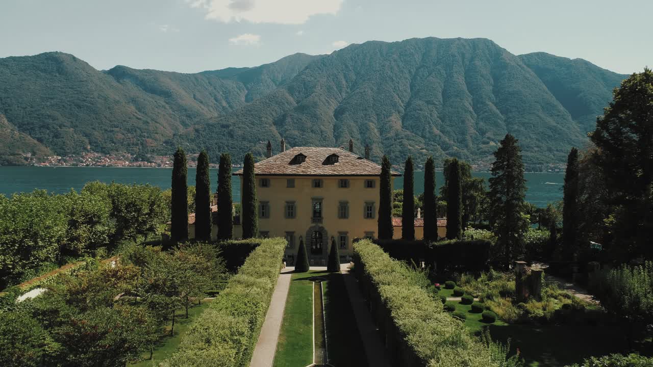 이탈리아의 코모 오수치오 호수에 있는 유명한 빌라 발비아노의 결혼식을 위해 앉아 있는 호수 앞 뒷마당을 드러내기 위해 아래로 기울어져 지붕 위의 앞 정원을 가로질러 날아갑니다.