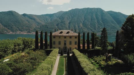 flying across the front garden over the roof tilting down to reveal seated backyard in front of the lake seated up for a wedding of famous villa balbiano at lake como ossuccio in italy