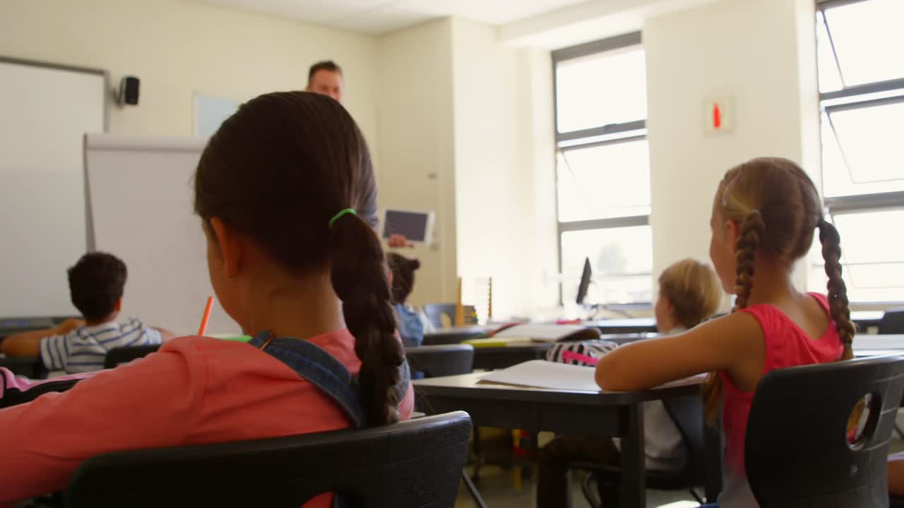 Insegnante maschio caucasico che usa un tablet digitale mentre insegna in classe 4k