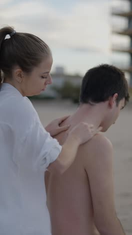 woman giving a neck and shoulder massage to a man outdoors