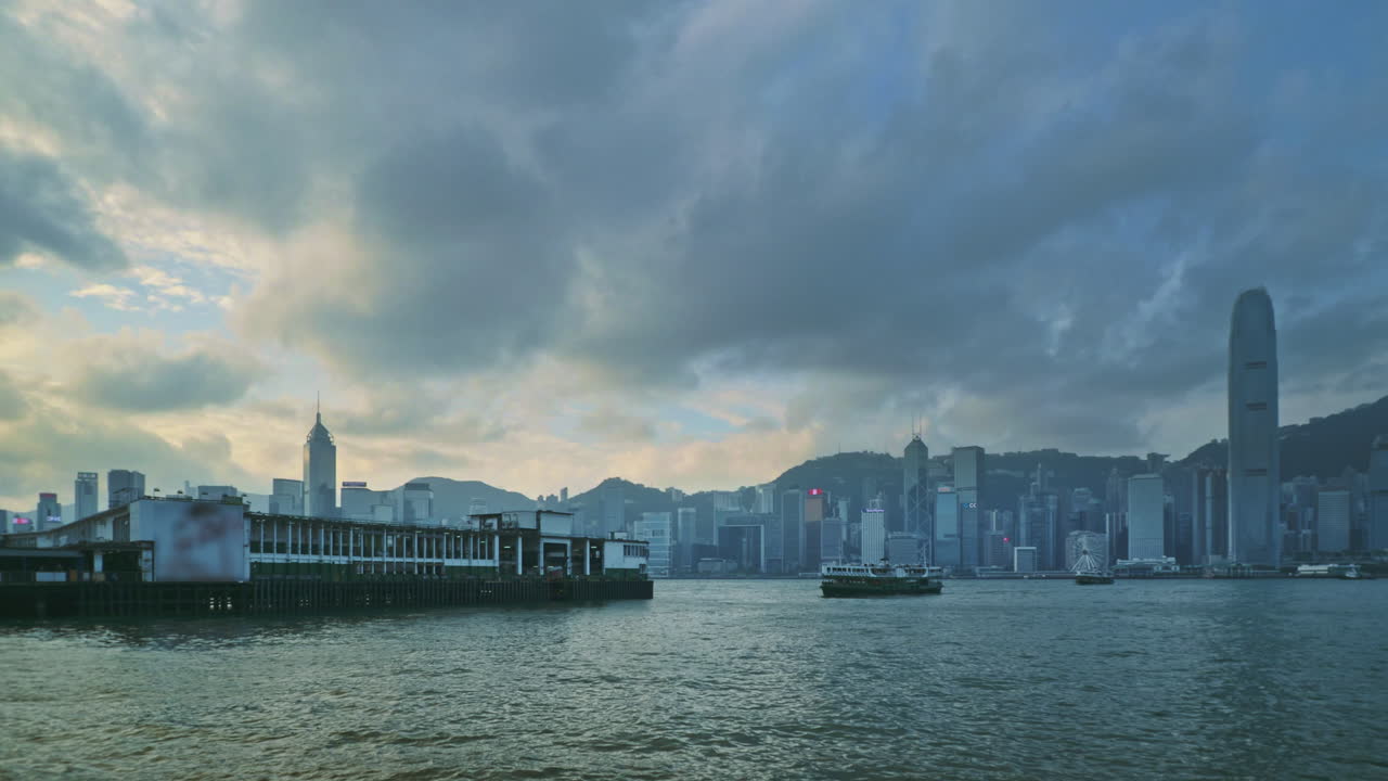 Skyline of Hong Kong island as seen from Kowloon waterfront at dusk. Locked low angle wide shot