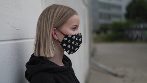 profile of young pretty female with face mask in city exterior, slow motion