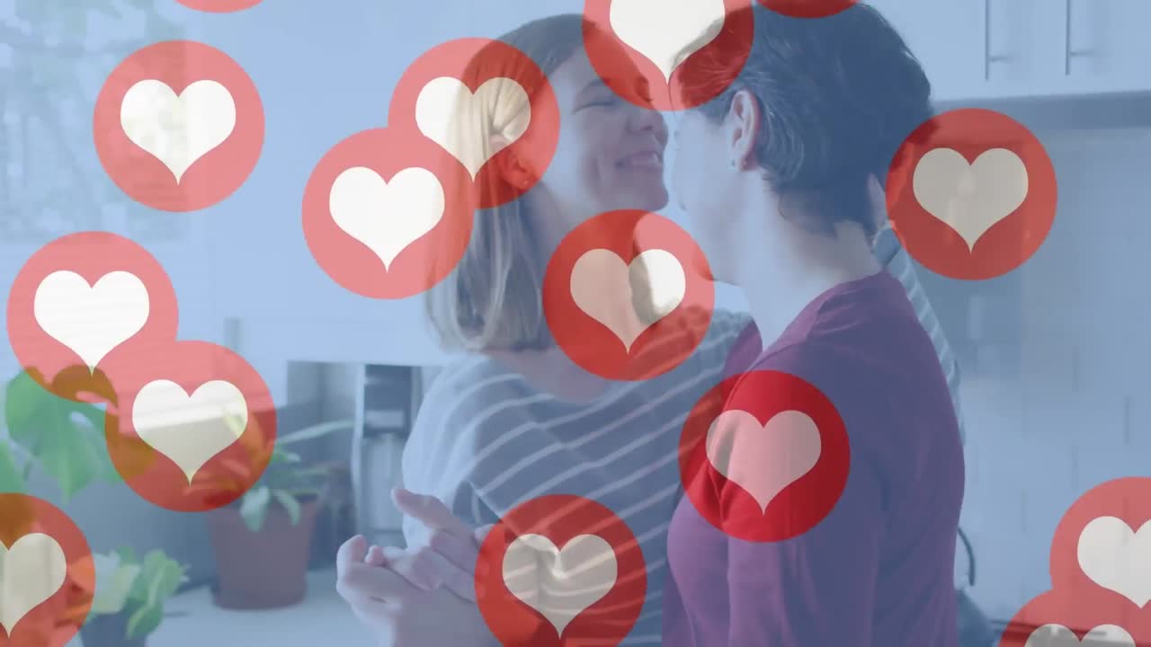 animación de emojis de corazón sobre una feliz pareja de mujeres caucásicas enamoradas abrazándose