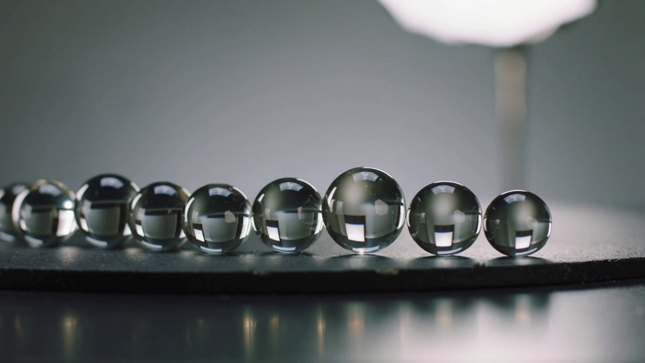 Rolling rightmost glass marble along strip on studio table after slight nudge showing lamp glow