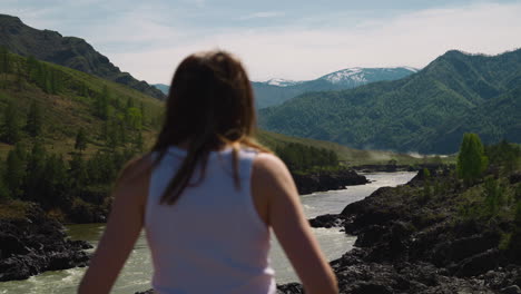 River-runs-across-mountain-valley-and-woman-on-sunny-day