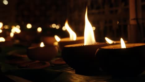 clay candles burn brightly against a soft, blurred background during yi peng celebration at night in chiang mai, thailand.
