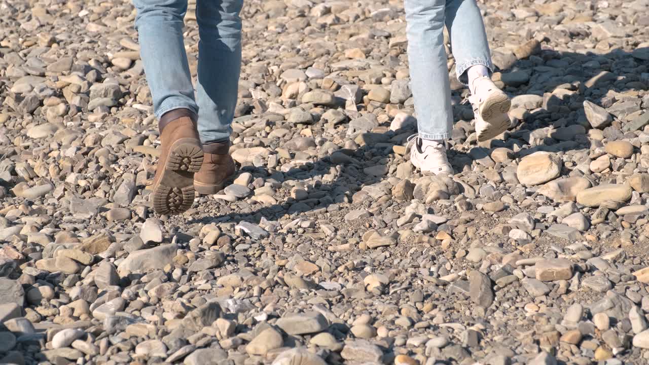 parejas de pies en zapatos caminando piedras de guijarros. pareja romántica caminando en una playa