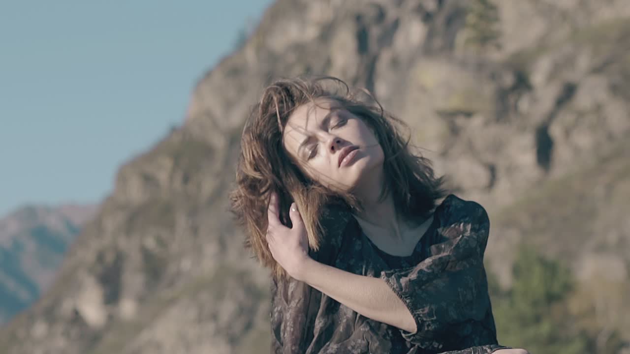 chica sensual en vestido posa ante el viento fuerte en un día soleado