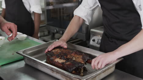 caucasian male chef taking out bones from roasted meat in kitchen, slow motion