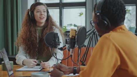 cheerful girl recording interview with guest at podcast studio