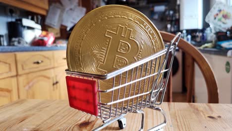 golden bitcoin crypto currency coins in tiny shopping trolley on kitchen table concept slow orbit left closeup